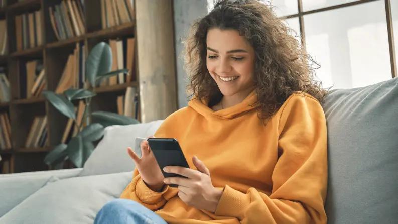 Woman sitting on sofa and using mobile