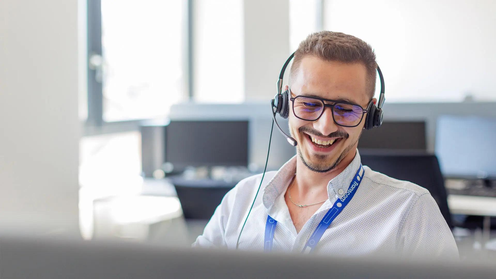A bearded man wearing a virtual reality headset, smiling and enjoying an immersive VR experience in a modern indoor setting.