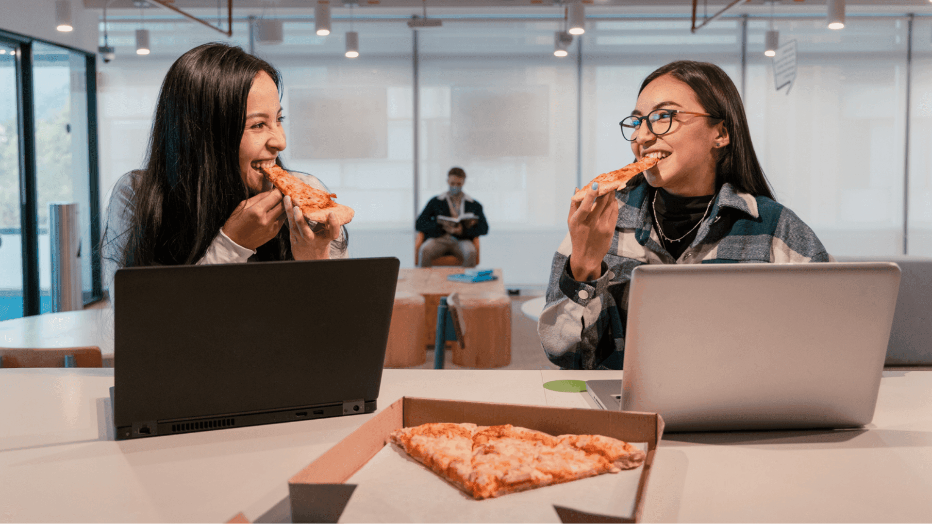 Food delivery service platform CX case study image showing two women eating pizza in a modern office.